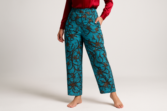 Model in dynamic pose wearing teal patterned pants